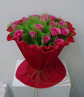 A bouquet of 19 pink roses with green foliages